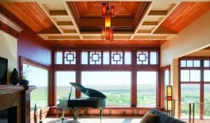A living room with a grand piano in front of picture windows with an expansive view of trees