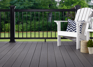 A gray deck featuring dark railing and a white patio chair