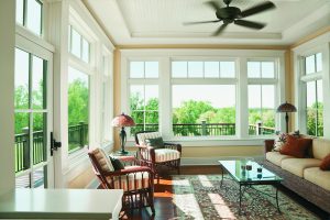 Large casement windows featured in an open-style living room complete with a couch, a table, and chairs