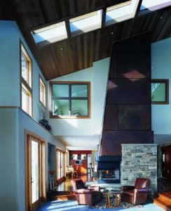 Two story home with a fireplace, sliding glass doors, and square skylights 