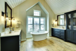 An expansive bathroom with large single-hung windows behind a white soaking tub