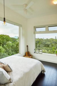 A bedroom with expansive windows showcasing treetops