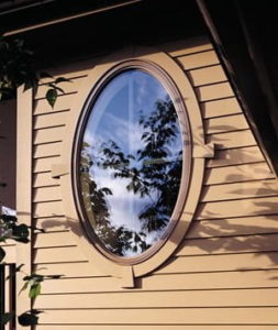 Large, oval shaped custom window on a house with brown siding