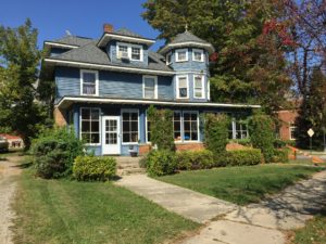 Blue multi-story home with bay and bow windows.