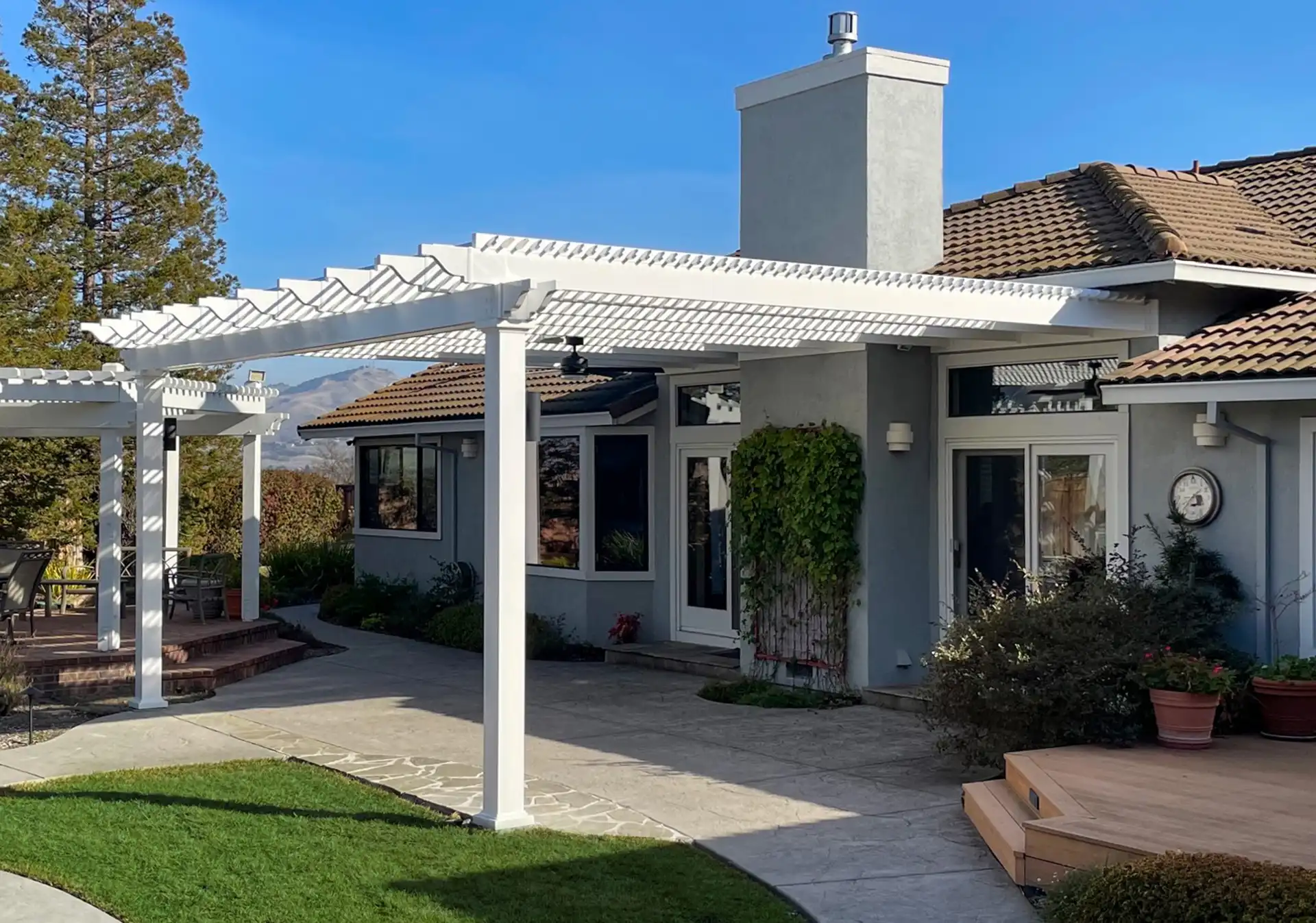 Pergola Design Ideas - Photo of an outdoor area with a couple of decks and patio with a pergola attached to the house over the patio and another pergola over a deck - Pergola Builders in Michigan