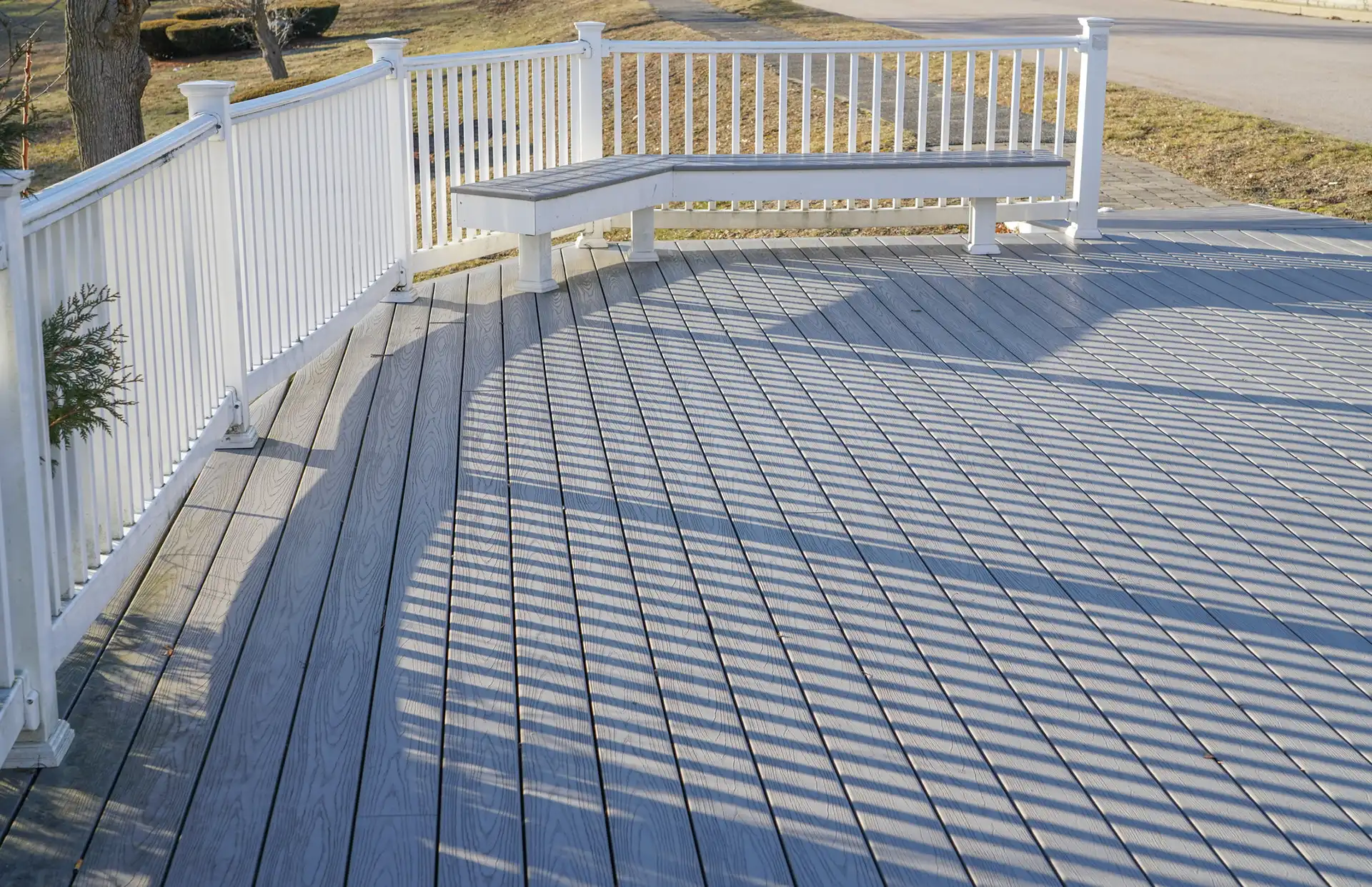 Photo of a curved deck with a built-in bench and white railing - Curved Deck Builders Michigan